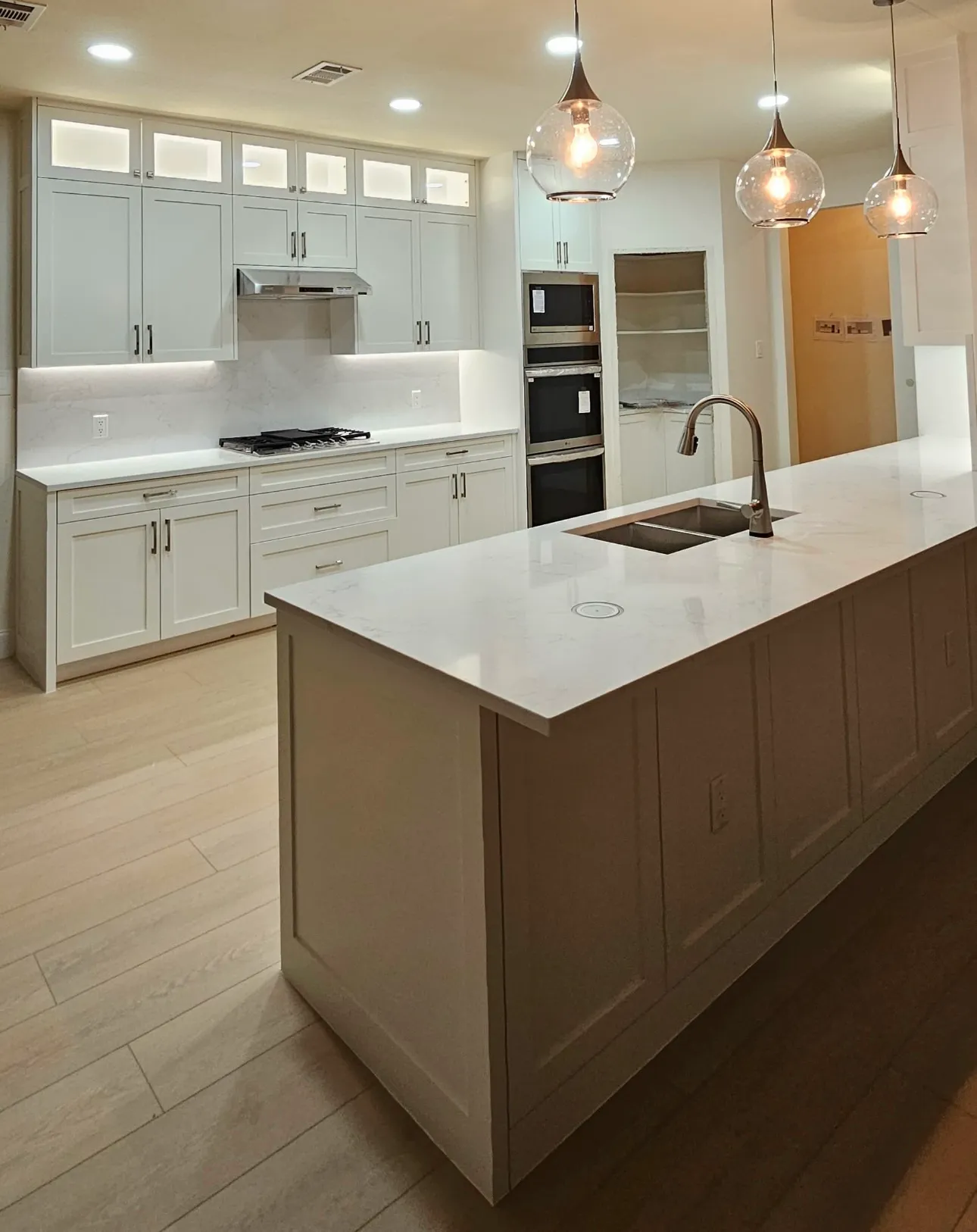 Modern kitchen with white cabinets, a large island, pendant lights, and built-in appliances.
