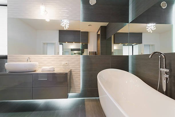 EE4F7232-F3F1-4AD4-9150-D698BD111AB4 Modern kitchen with white cabinets, marble island, four barstools, pendant lights, and wood accents.