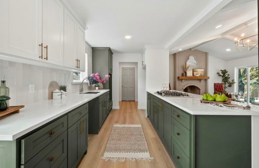 93FE9E07-1A2C-450B-8D72-0945068D5EF6 Modern kitchen with white cabinets, a large island, pendant lights, and wooden accents.