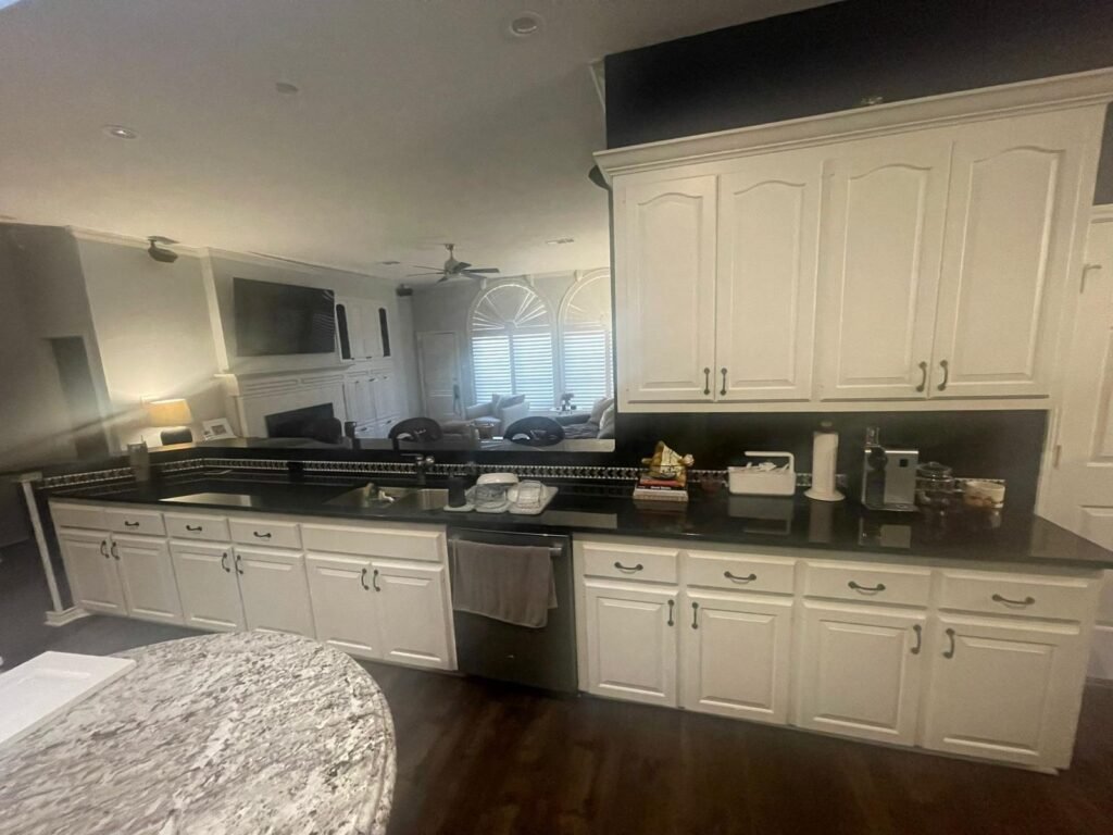 Modern kitchen with white cabinets, a large island, pendant lights, and wooden accents.