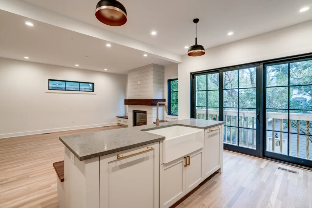 Modern kitchen with white cabinets, a large island, pendant lights, and wooden accents.
