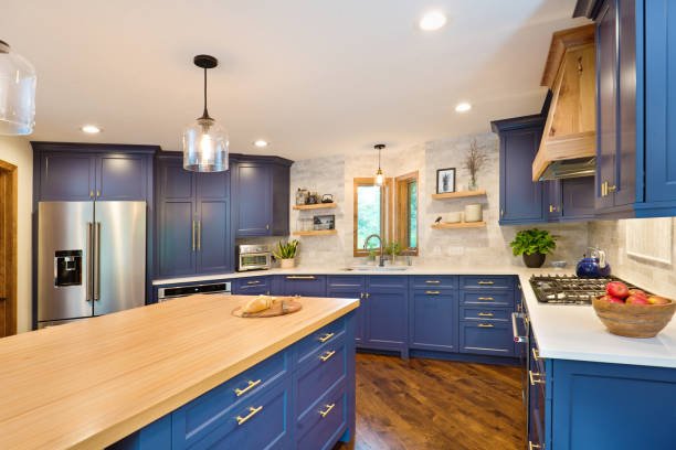Modern kitchen with white cabinets, a large island, pendant lights, and wooden accents.
