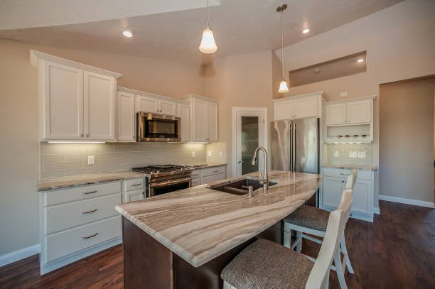 Modern kitchen with white cabinets, a large island, pendant lights, and wooden accents.