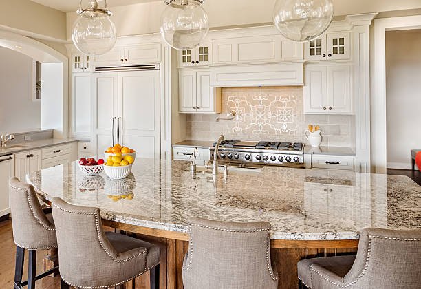Modern kitchen with white cabinets, a large island, pendant lights, and wooden accents.