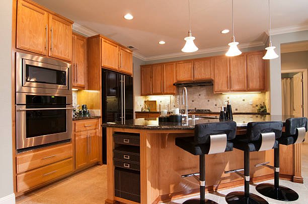Modern kitchen with white cabinets, a large island, pendant lights, and wooden accents.