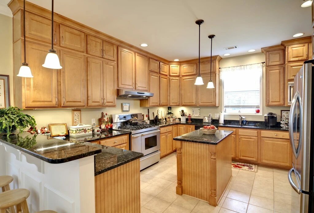 Modern kitchen with white cabinets, a large island, pendant lights, and wooden accents.