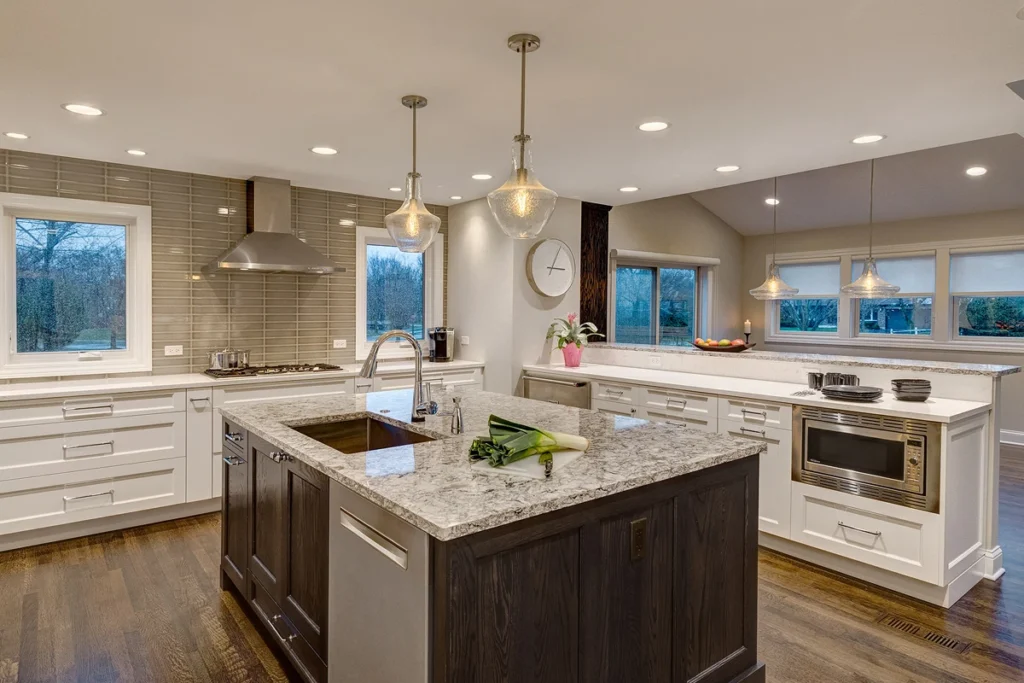 Modern kitchen with white cabinets, a large island, pendant lights, and wooden accents.