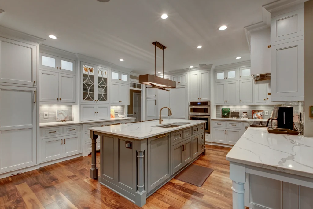 Modern kitchen with white cabinets, a large island, pendant lights, and wooden accents.