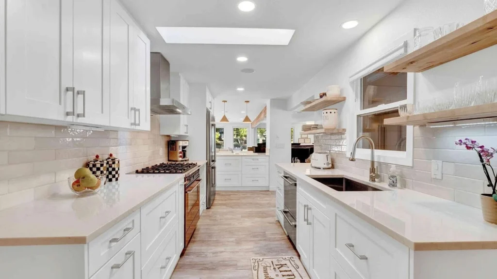 Modern kitchen with white cabinets, a large island, pendant lights, and wooden accents.