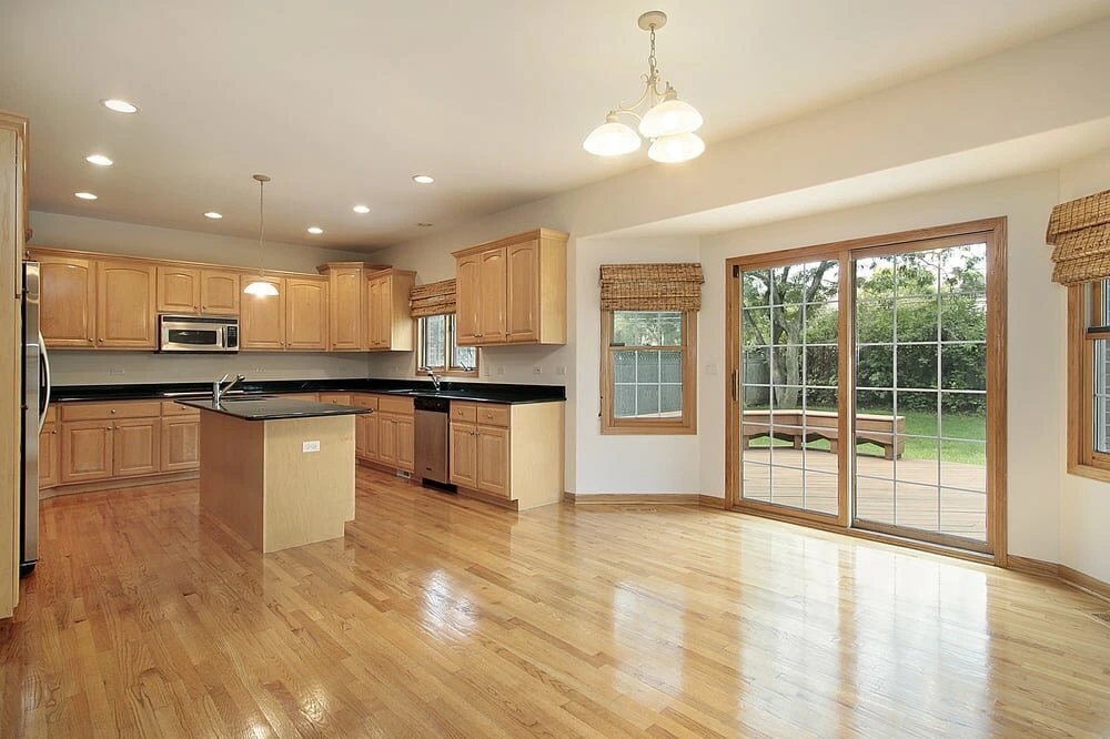 Modern kitchen with white cabinets, a large island, pendant lights, and wooden accents.