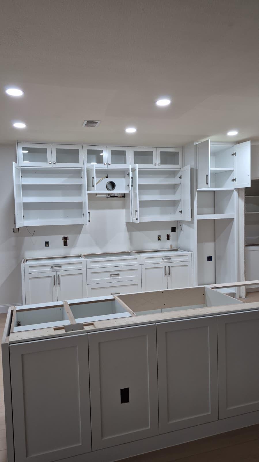 Modern kitchen with white cabinets, marble island, four barstools, pendant lights, and wood accents.