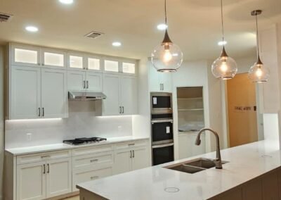 White Shaker Kitchen Remodel with Wall Ovens and Lit Glass Cabinets