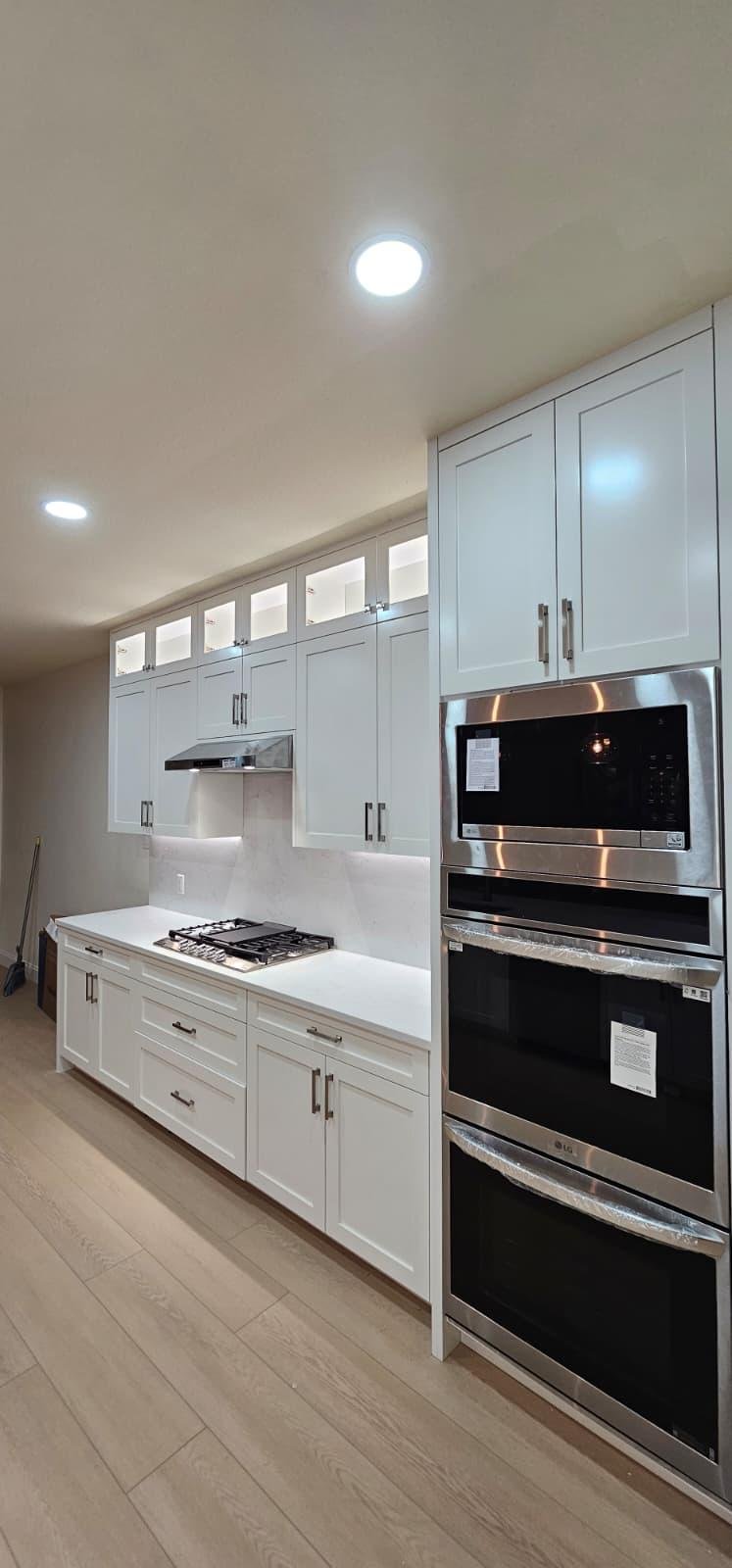 Modern kitchen with white cabinets, marble island, four barstools, pendant lights, and wood accents.