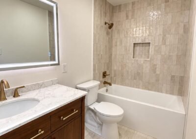Bathroom Remodel with Walnut Vanity, Vertical Tile Tub Surround, and Brushed Brass Fixtures